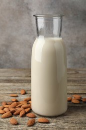 Fresh nut milk in jug and almonds on wooden table