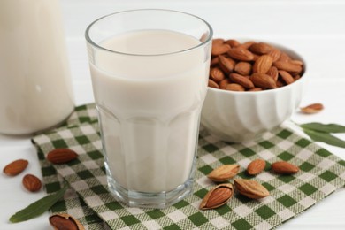 Photo of Fresh nut milk and almonds on white table, closeup