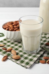 Fresh nut milk and almonds on white table, closeup