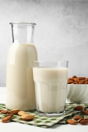 Photo of Fresh nut milk and almonds on white wooden table