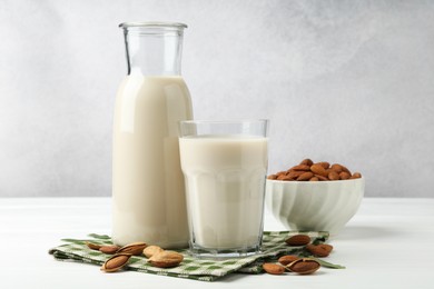 Photo of Fresh nut milk and almonds on white wooden table