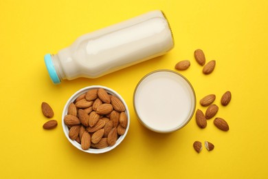 Photo of Fresh nut milk and almonds on yellow background, flat lay