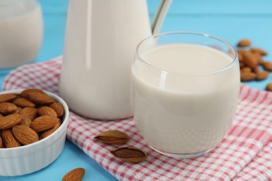 Fresh nut milk and almonds on light blue table, closeup