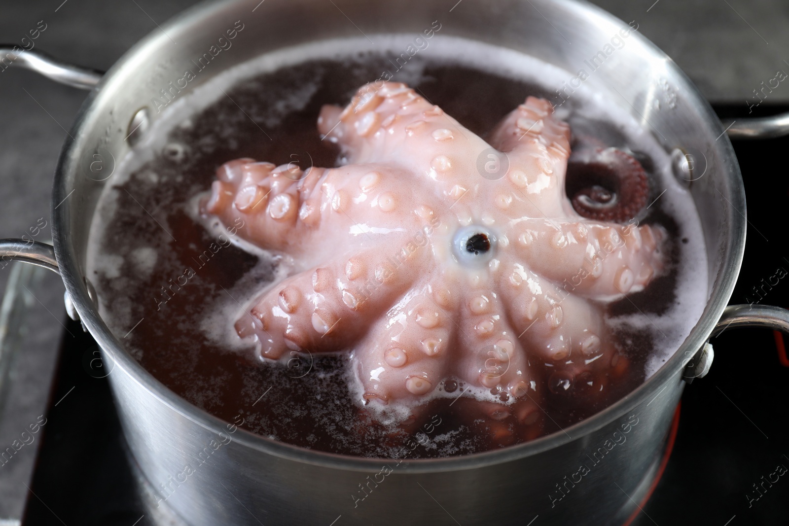 Photo of Fresh octopus boiling in pan on stove, closeup