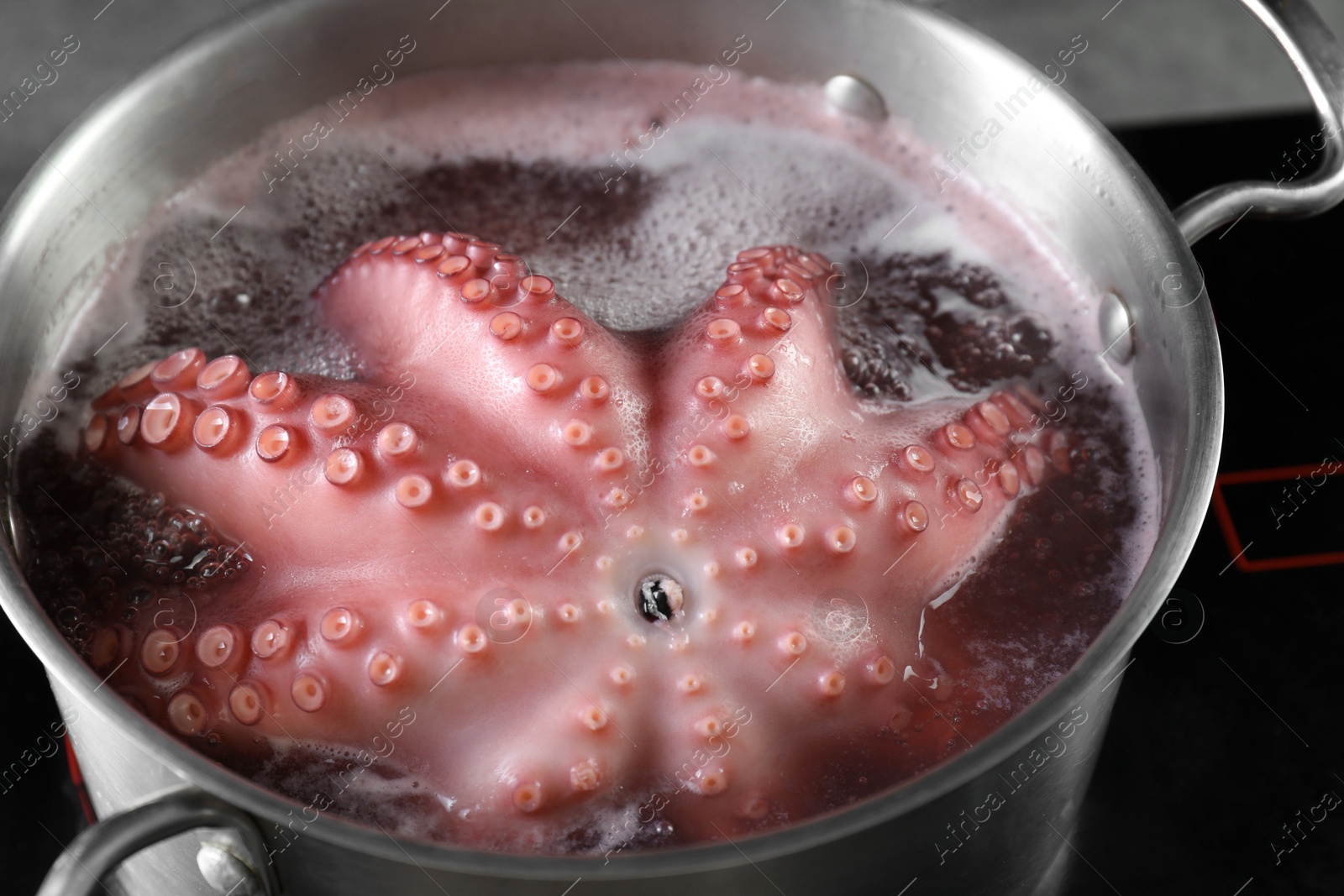 Photo of Fresh octopus boiling in pan on stove, closeup