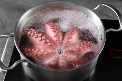 Photo of Fresh octopus boiling in pan on stove, closeup