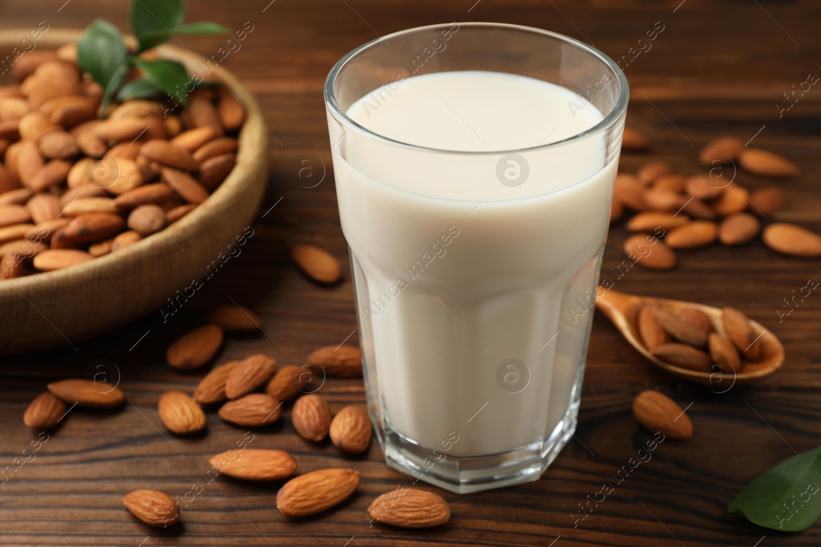 Photo of Fresh almond milk in glass and nuts on wooden table, closeup