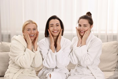 Happy woman wearing bathrobes on sofa in spa