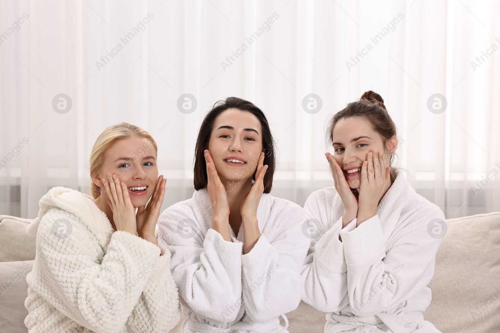 Photo of Happy woman wearing bathrobes on sofa in spa