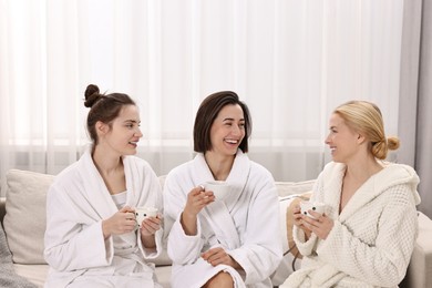 Beautiful women having tea on sofa in spa