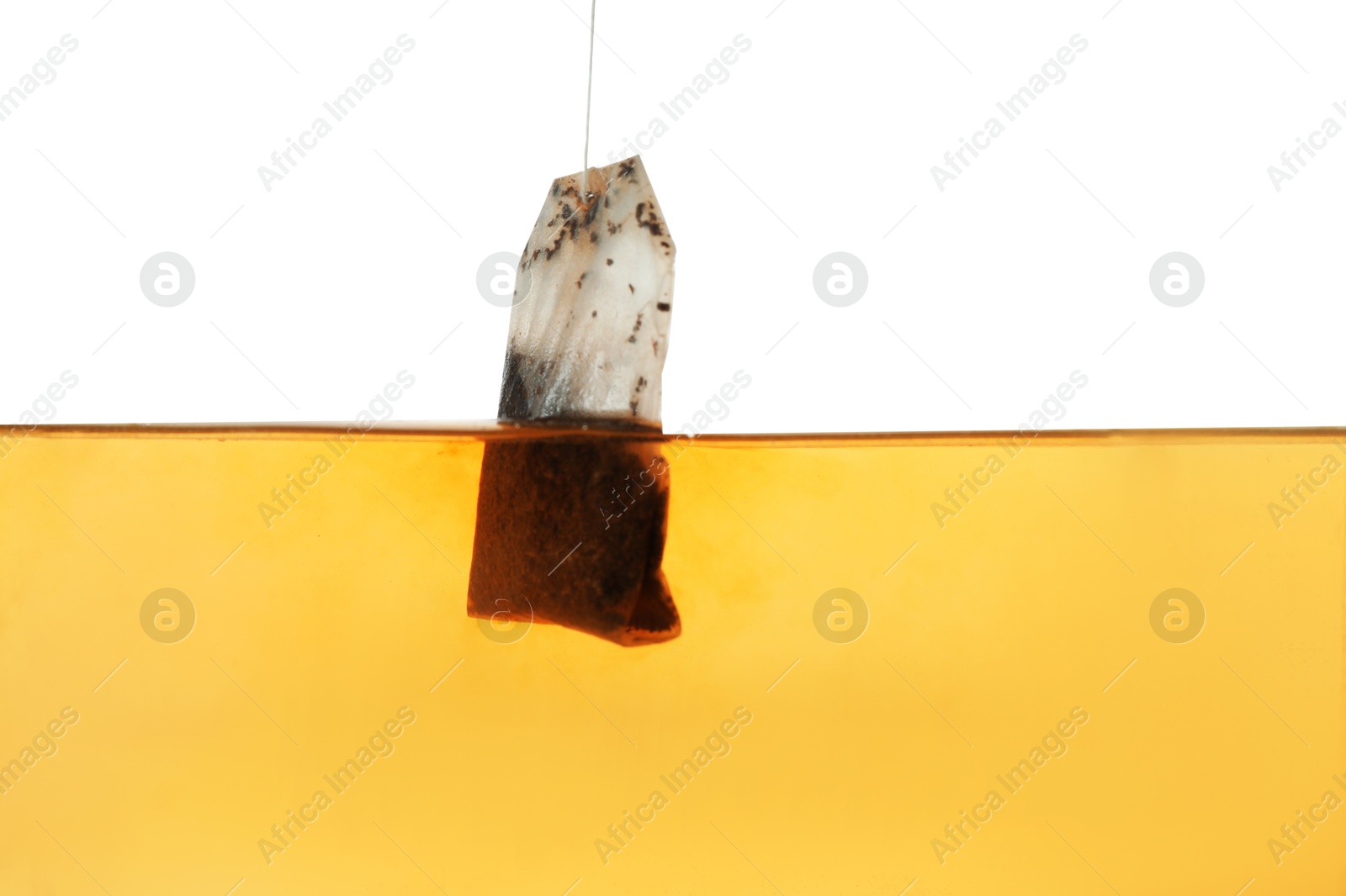 Photo of Putting tea bag into glass cup on white background, closeup