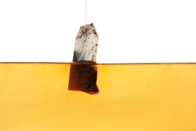 Putting tea bag into glass cup on white background, closeup