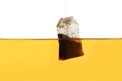 Putting tea bag into glass cup on white background, closeup