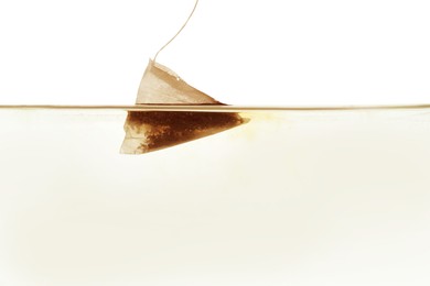 Putting tea bag into glass cup on white background, closeup