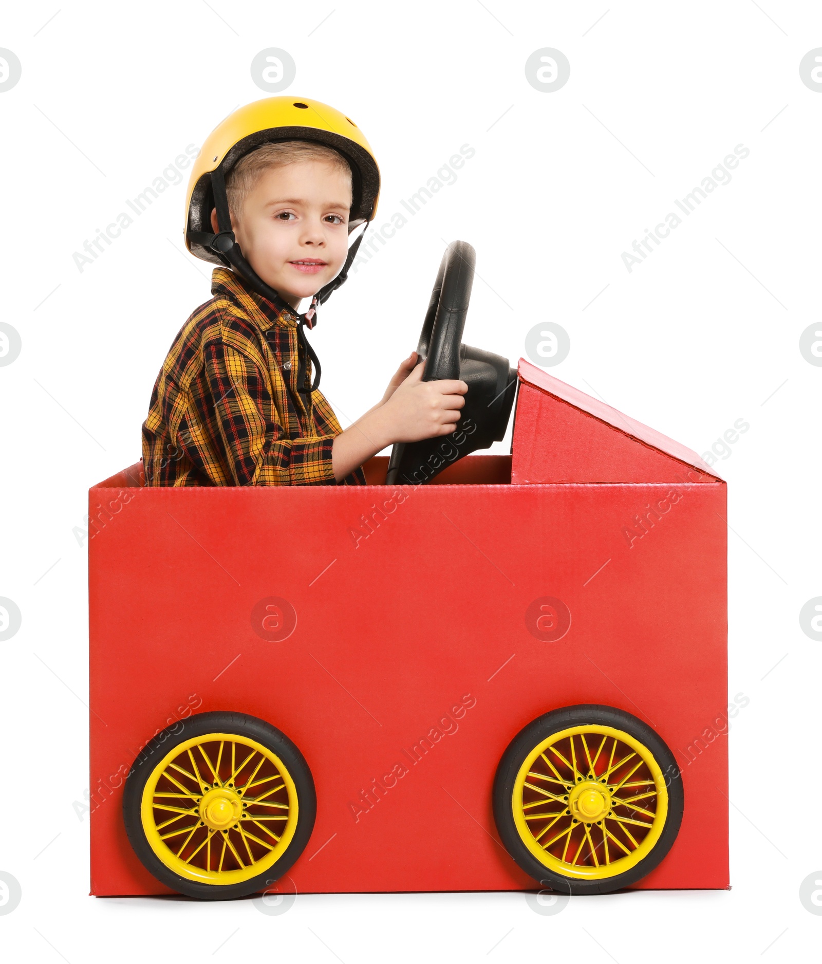 Photo of Little boy driving car made of cardboard on white background