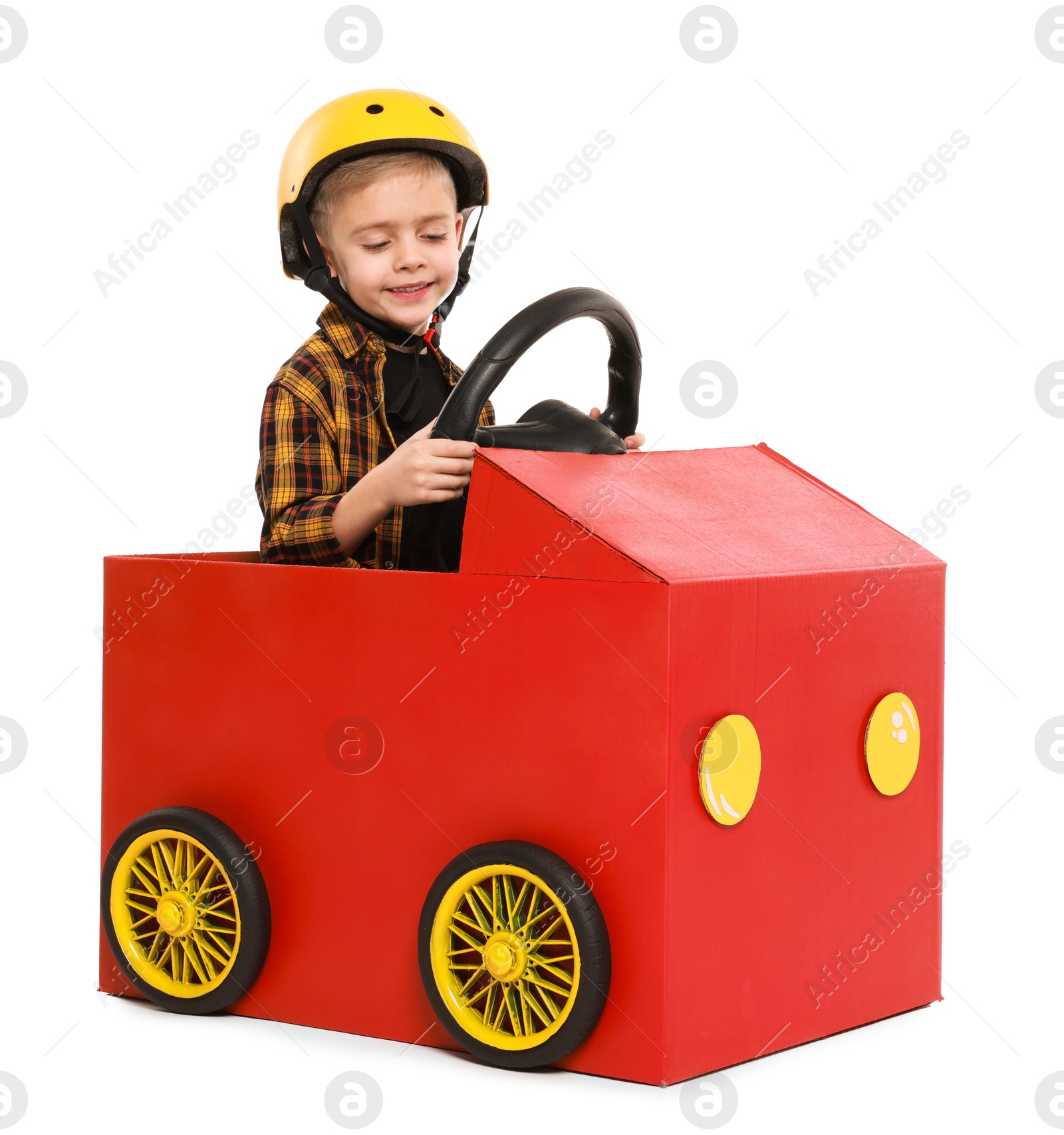 Photo of Little boy driving car made of cardboard on white background