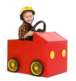 Little boy driving car made of cardboard on white background