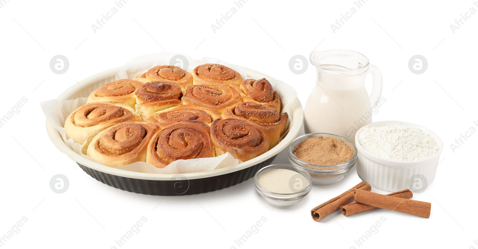 Photo of Freshly baked cinnamon rolls in baking dish and ingredients isolated on white