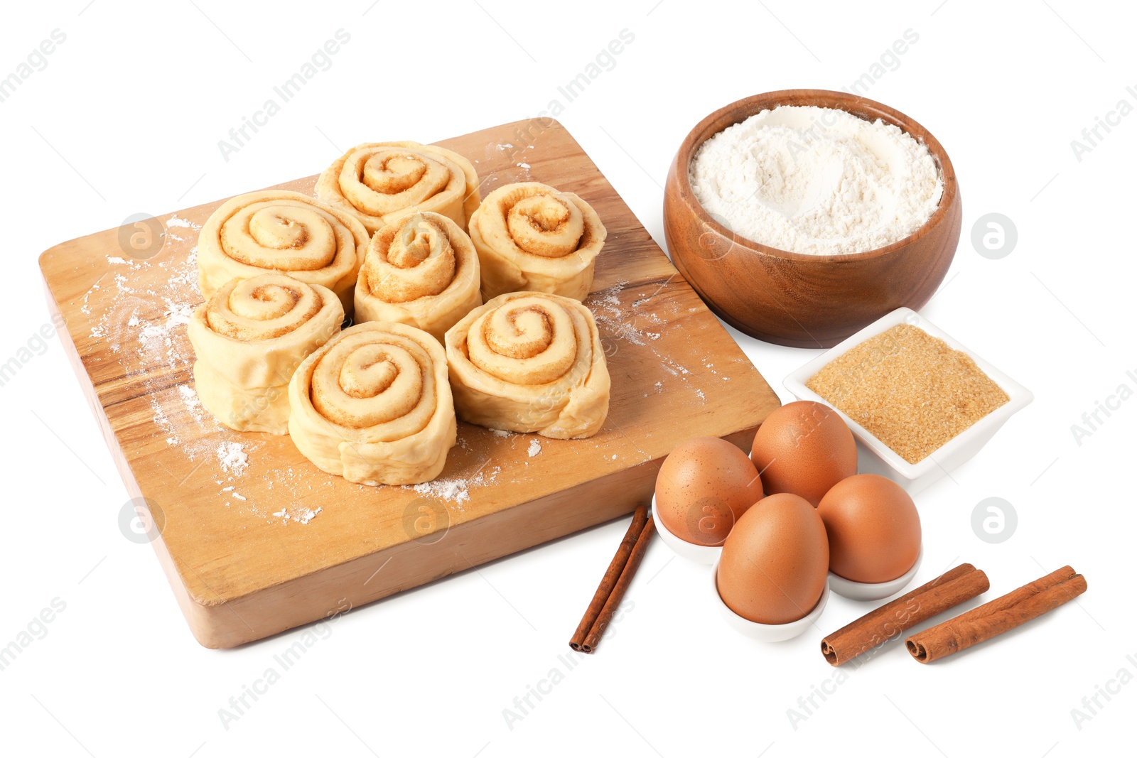 Photo of Raw cinnamon rolls and different ingredients isolated on white