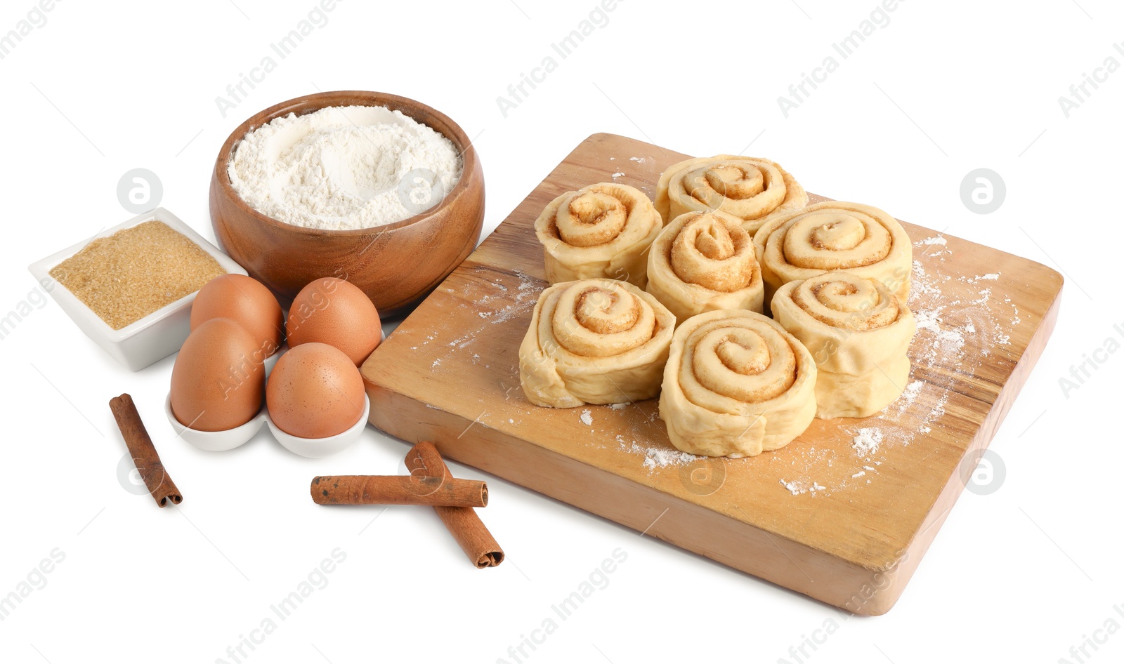 Photo of Raw cinnamon rolls and different ingredients isolated on white