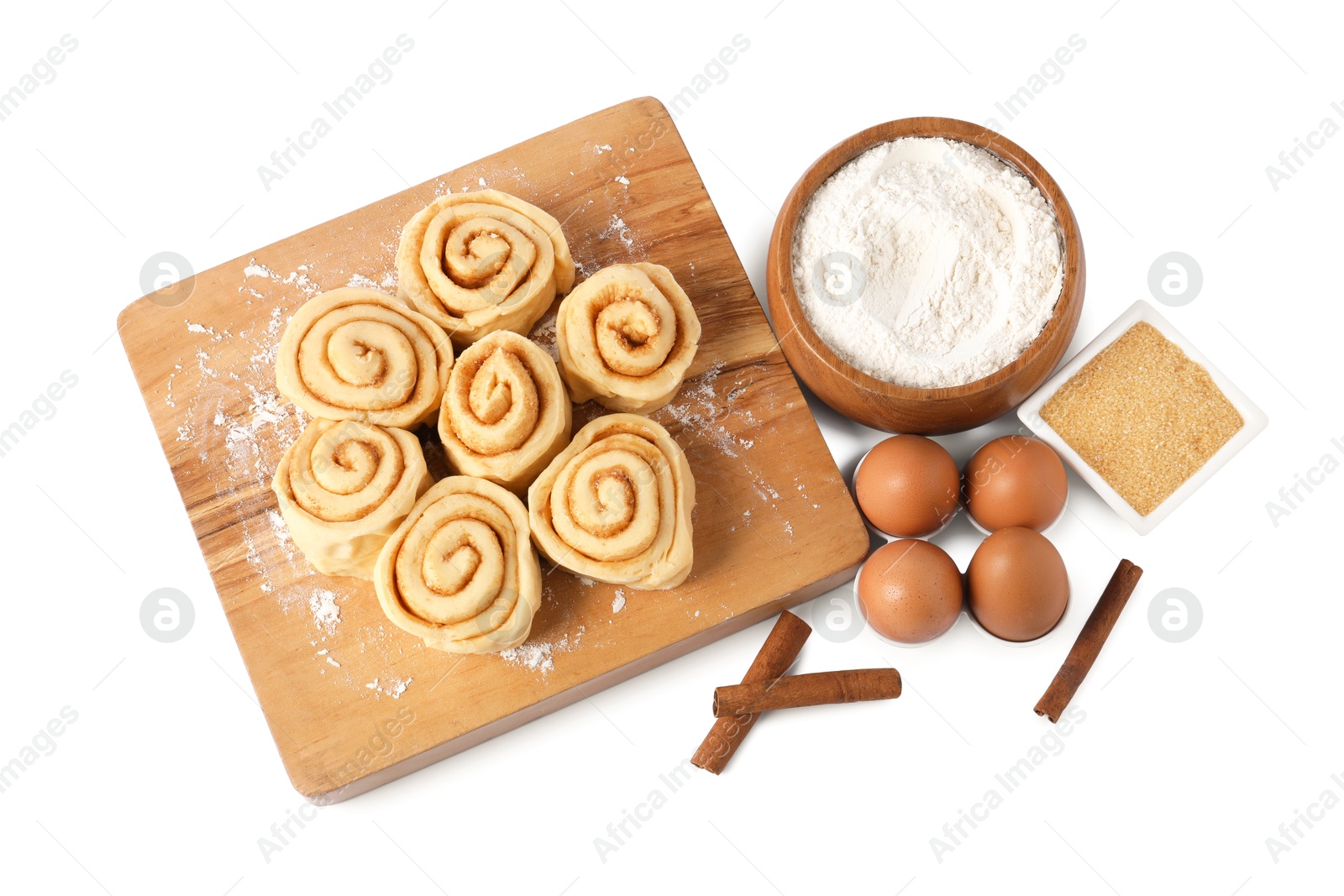 Photo of Raw cinnamon rolls and different ingredients isolated on white, top view