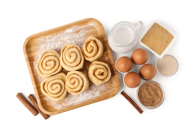 Photo of Raw cinnamon rolls and different ingredients isolated on white, top view