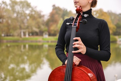 Photo of Young woman with cello in park, closeup. Space for text