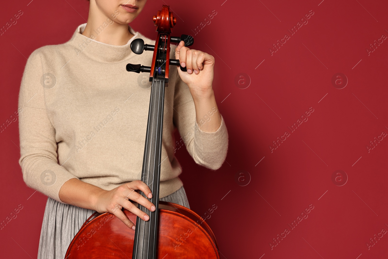 Photo of Young woman with cello on red background, closeup. Space for text