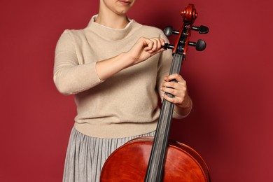 Photo of Young woman with cello on red background, closeup