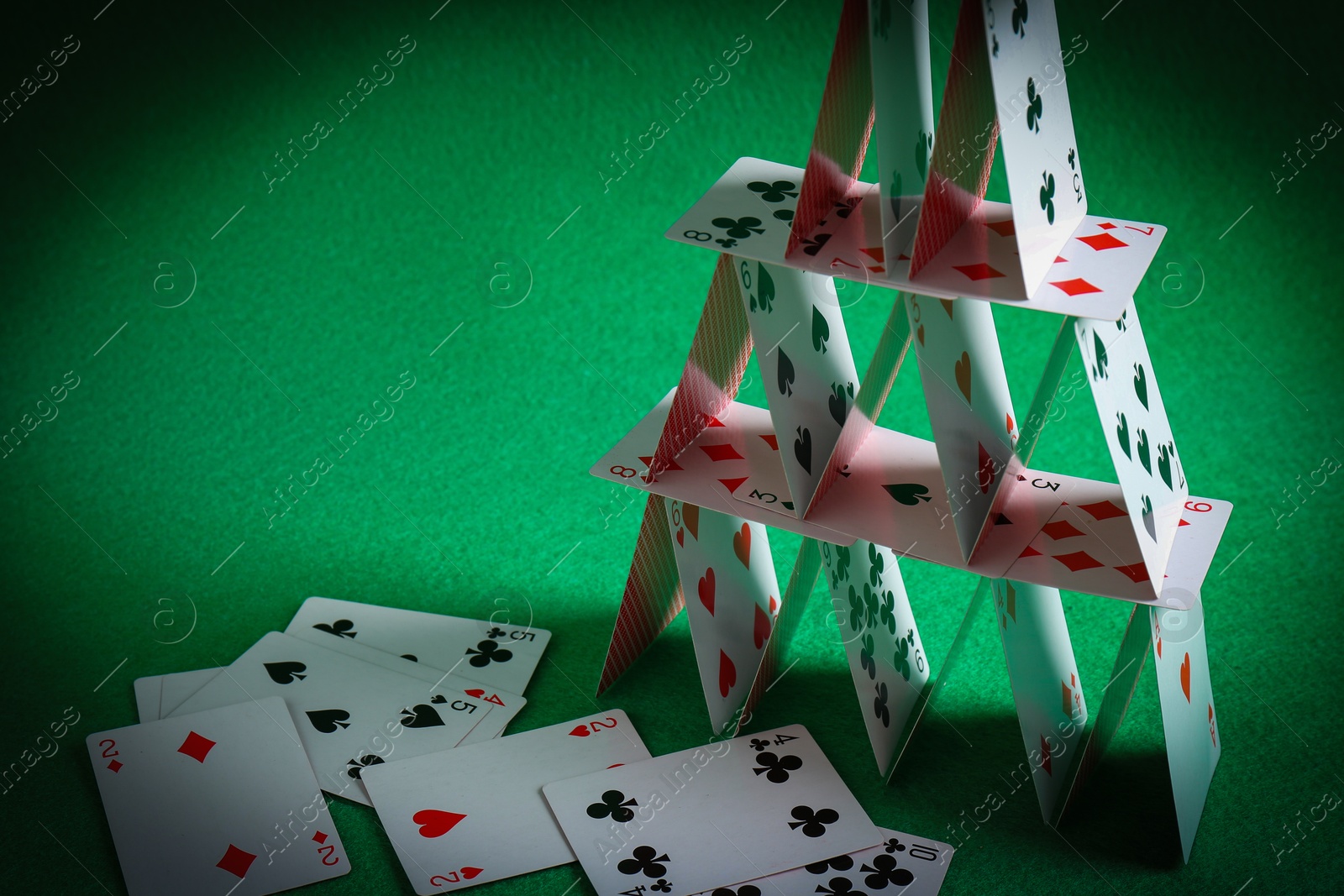 Photo of House of playing cards on green background