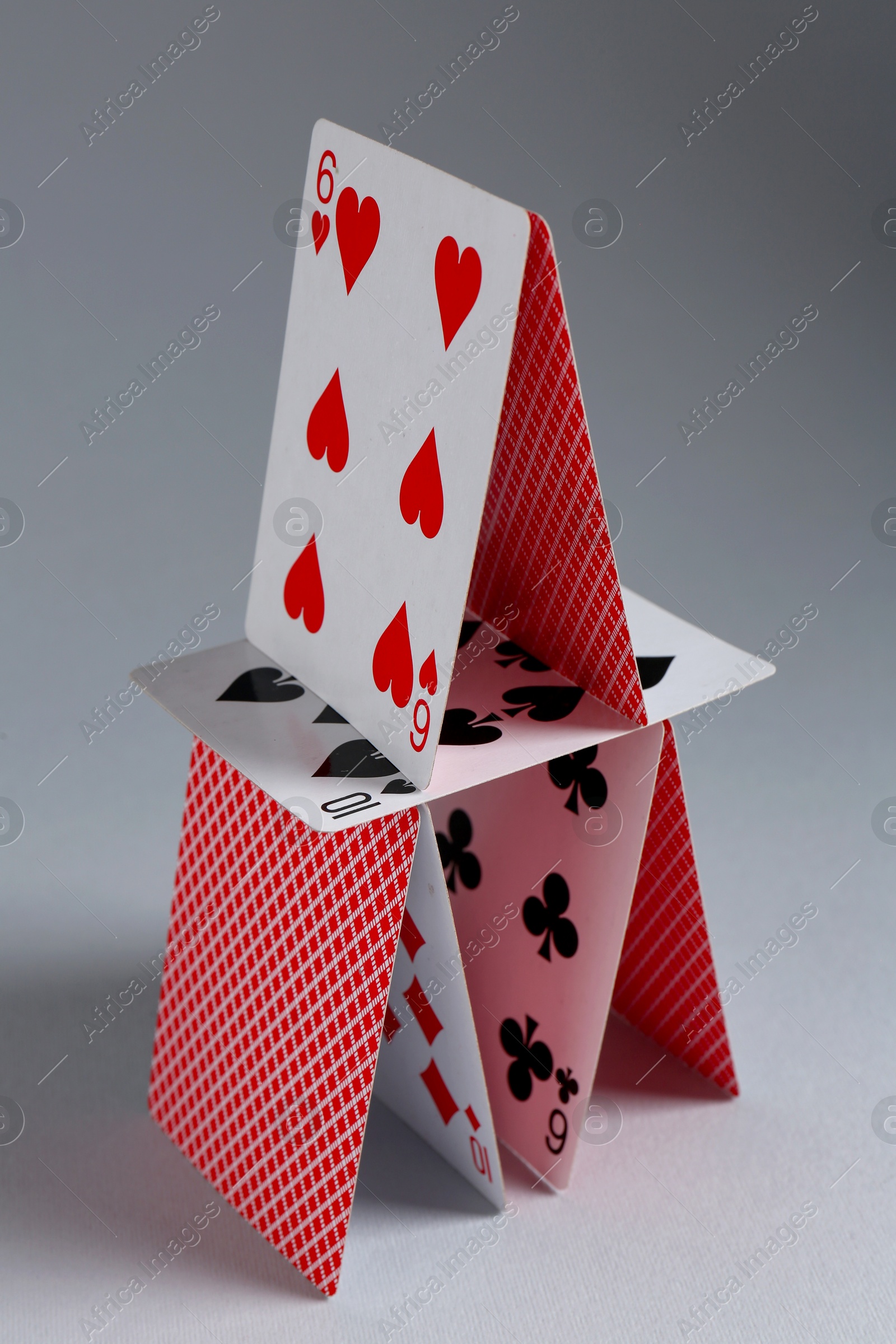 Photo of House of playing cards on light grey background