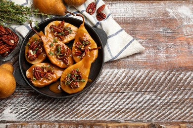 Photo of Delicious pears with caramel sauce, pecan nuts and thyme on wooden table, top view. Space for text