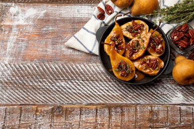 Photo of Delicious pears with caramel sauce, pecan nuts and thyme on wooden table, top view. Space for text