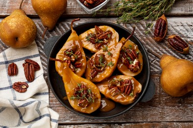 Photo of Delicious pears with caramel sauce, pecan nuts and thyme on wooden table, top view