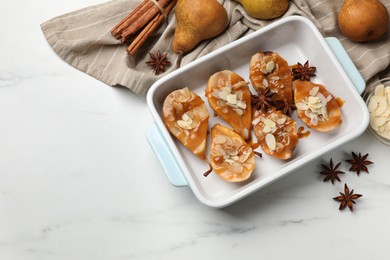 Photo of Delicious pears with caramel sauce, almond flakes and spices on white marble table, top view. Space for text