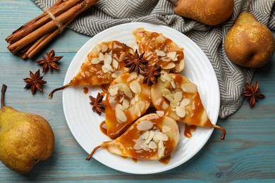 Photo of Delicious pears with caramel sauce, almond flakes and spices on light blue wooden table, flat lay