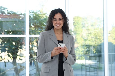 Photo of Portrait of young woman with phone wearing stylish suit indoors