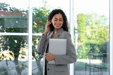 Photo of Portrait of young woman with laptop wearing stylish suit indoors