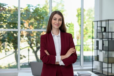 Portrait of young woman with laptop wearing stylish suit indoors