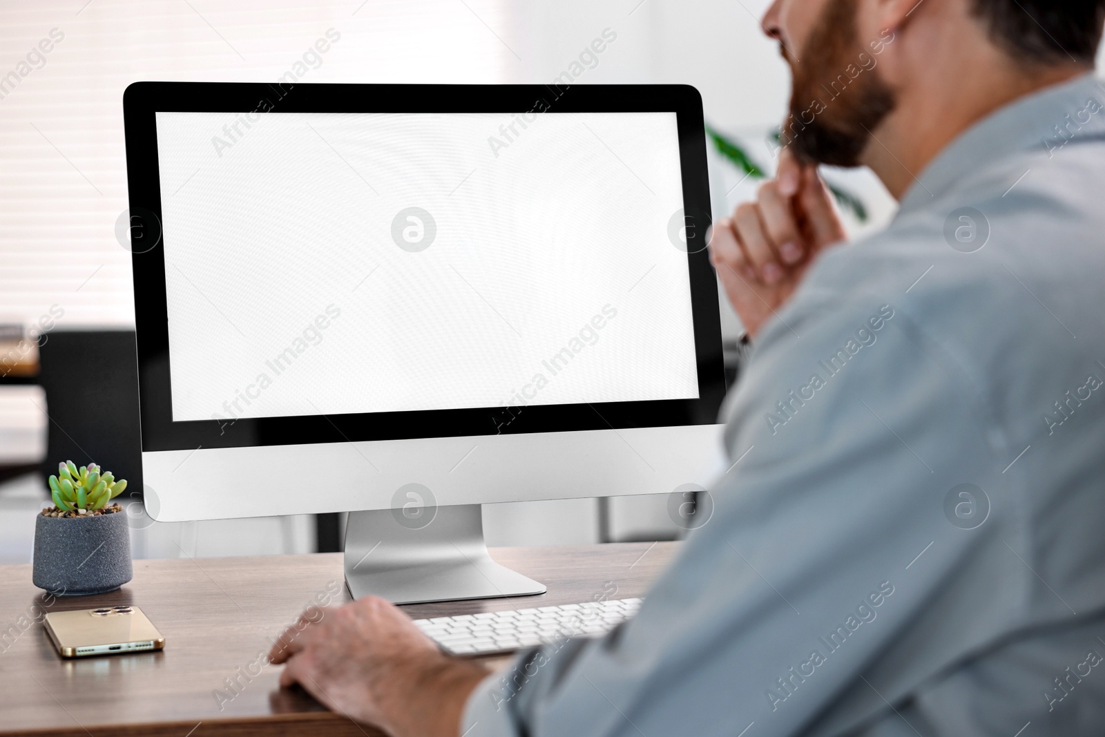 Photo of Man working on computer at table in office, closeup