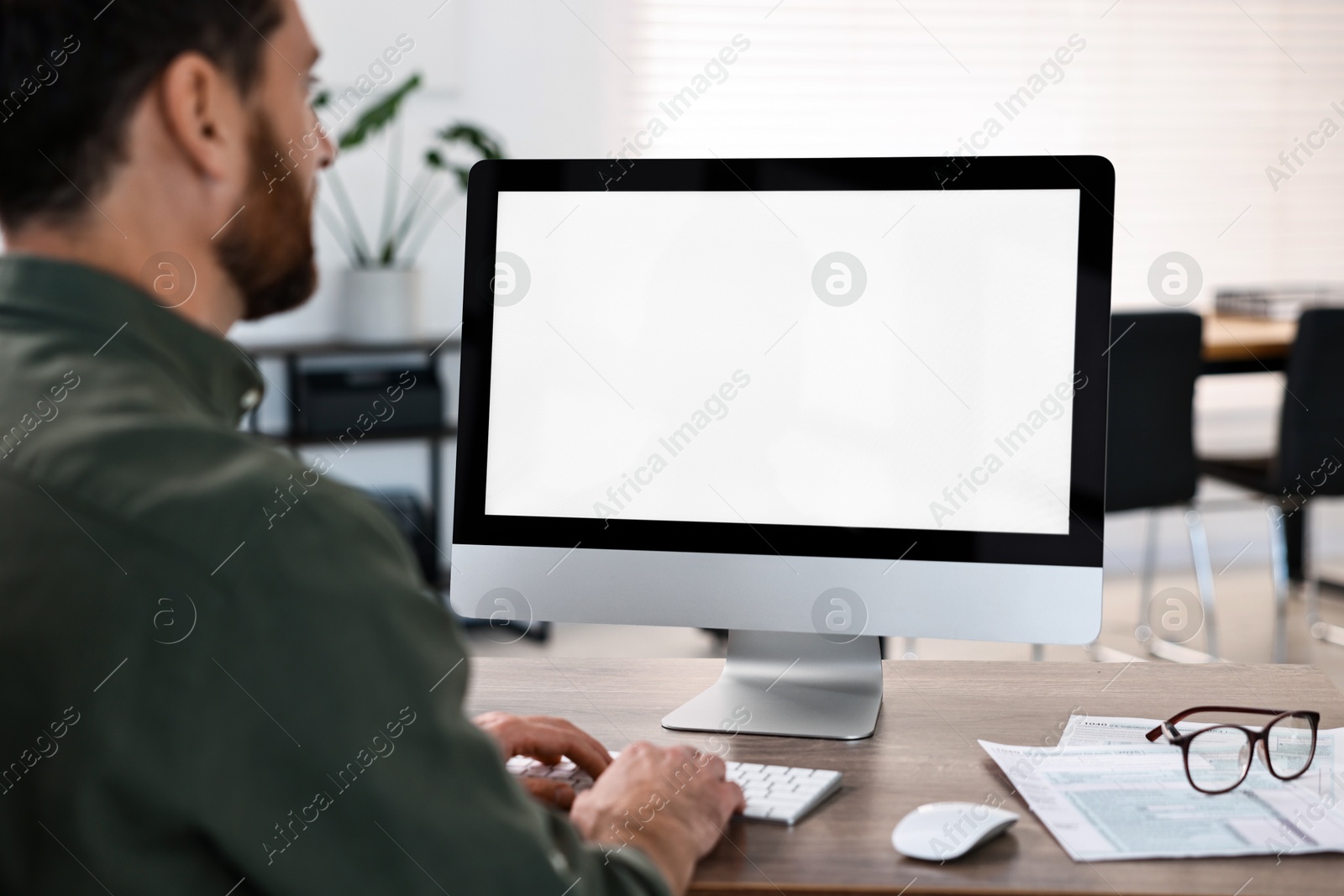 Photo of Man working on computer at table in office, closeup