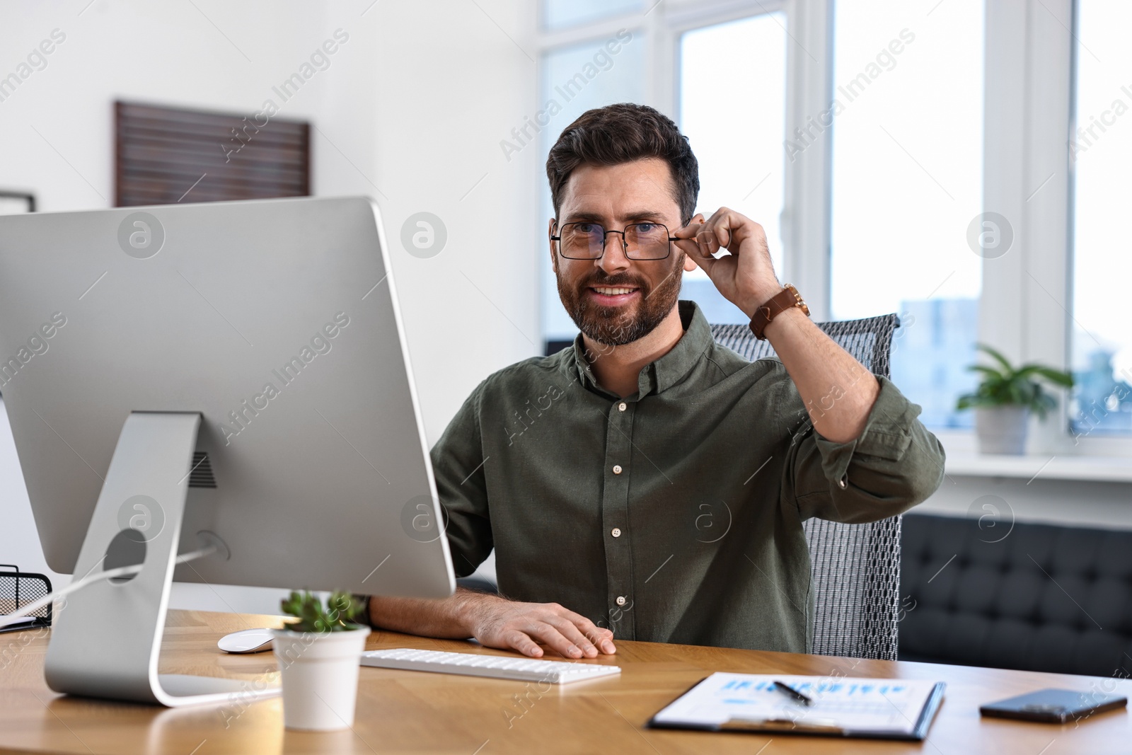 Photo of Portrait of man at table with computer in office