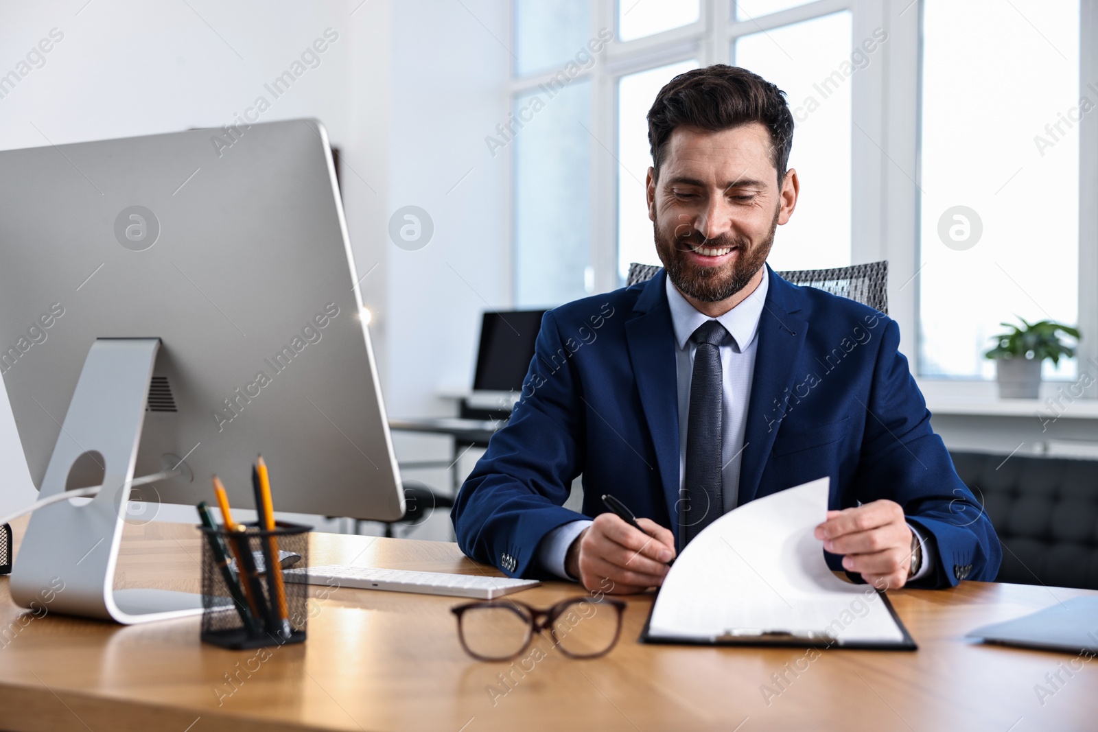 Photo of Man with document working at table in office