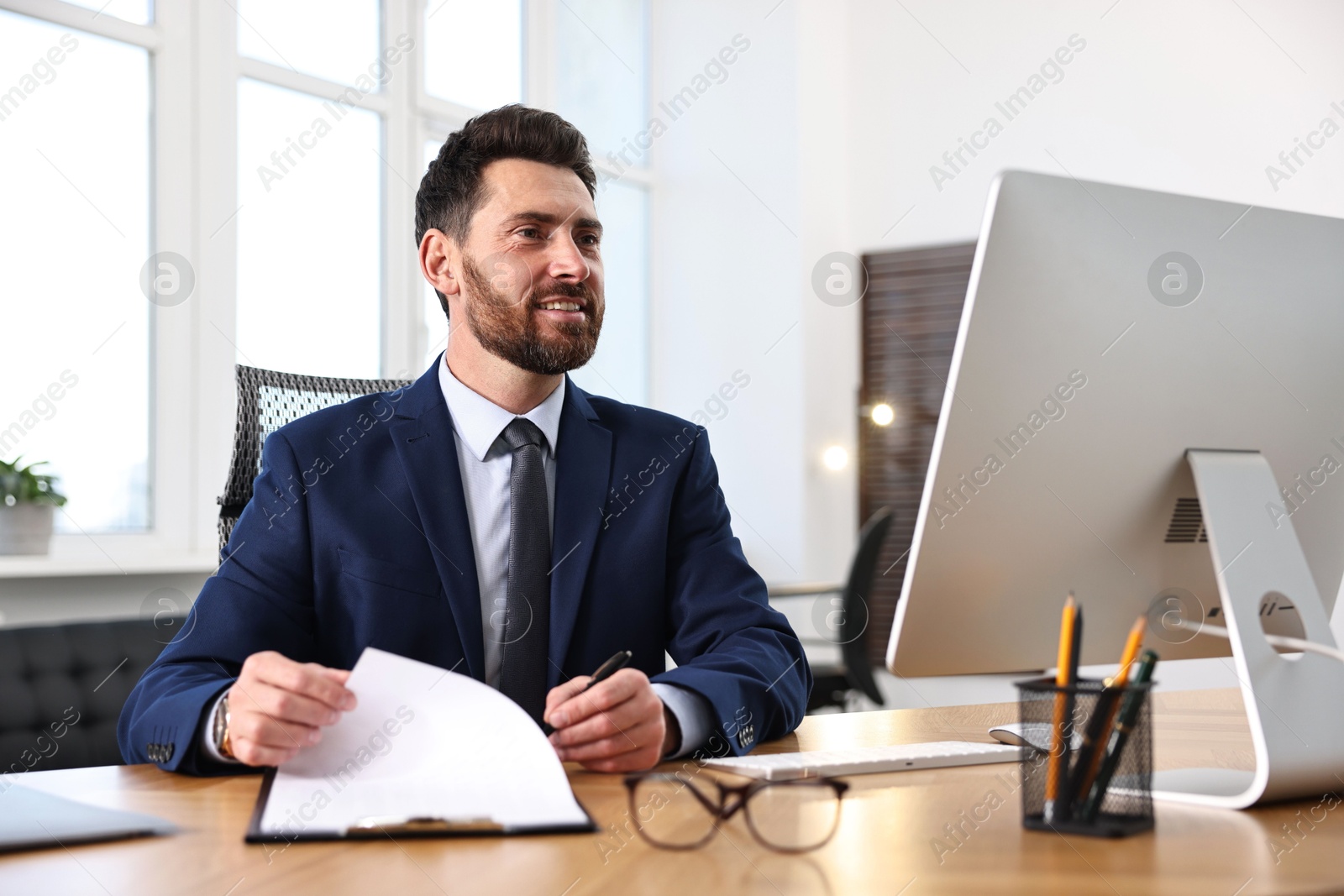 Photo of Man with document working at table in office