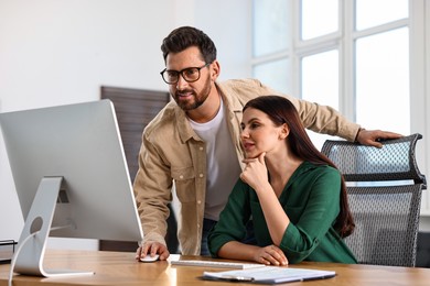 Photo of Colleagues working with computer at desk in office