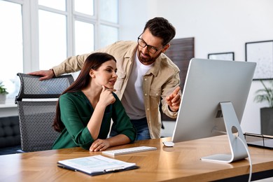 Photo of Colleagues working with computer at desk in office