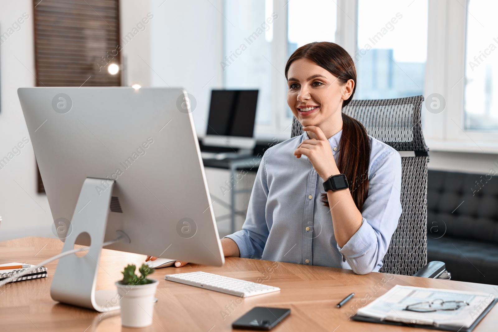 Photo of Woman working on computer at table in office