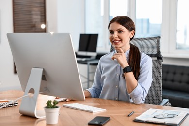 Photo of Woman working on computer at table in office