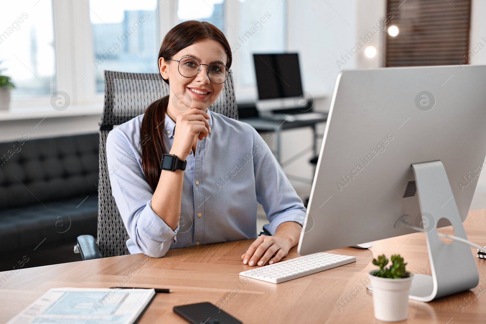 Photo of Portrait of woman at table with computer in office