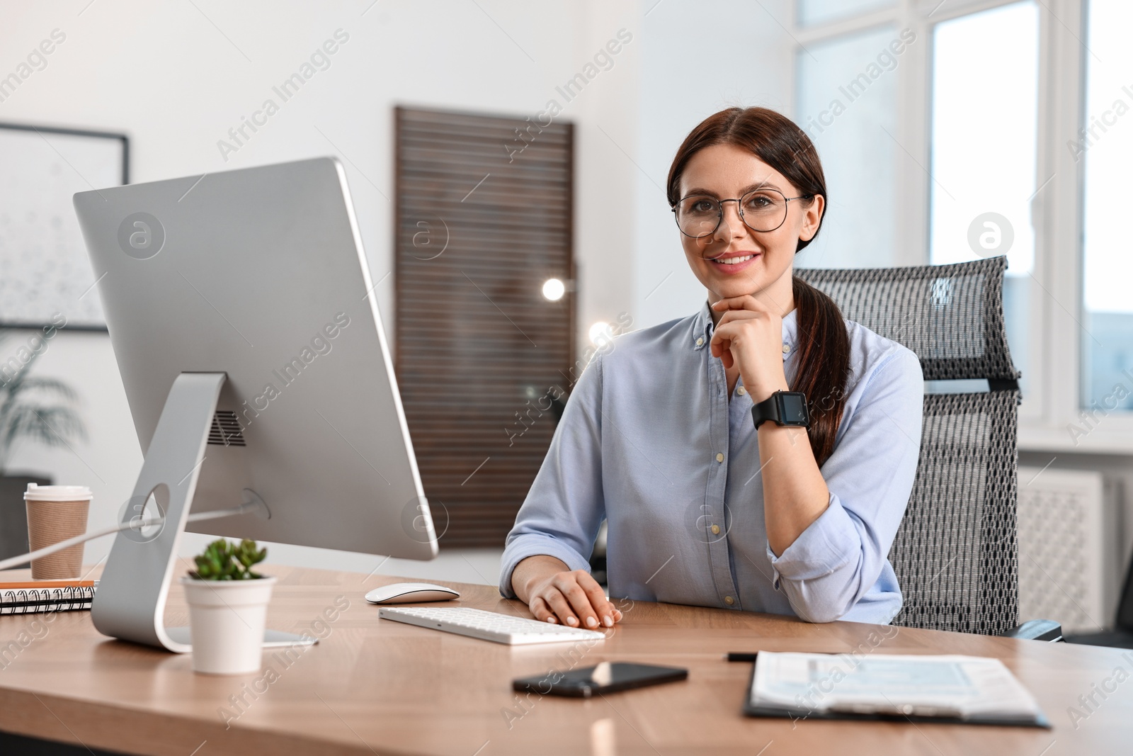 Photo of Portrait of woman at table with computer in office